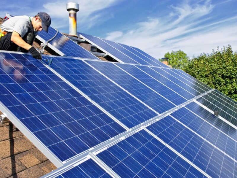A man installing solar panels on a roof