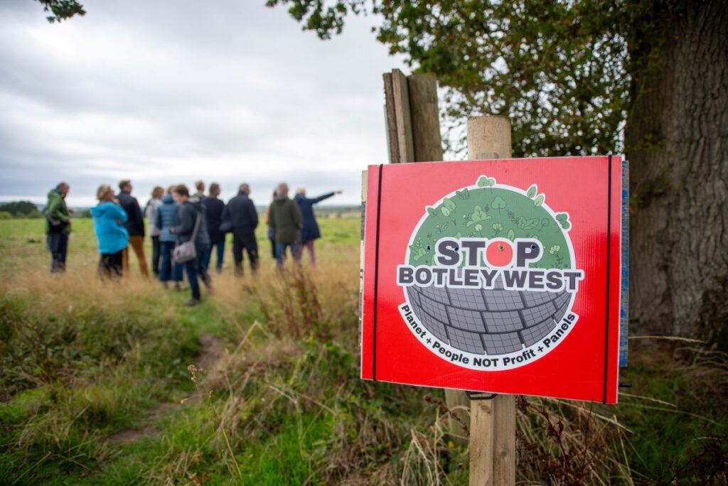 A 'Stop Botley West' placard with a group of people in the background