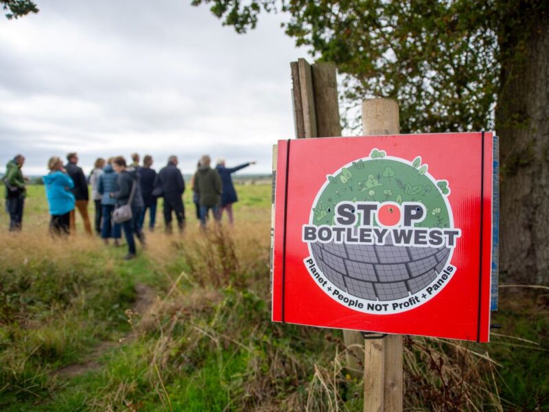 A 'Stop Botley West' placard with a group of people in the background
