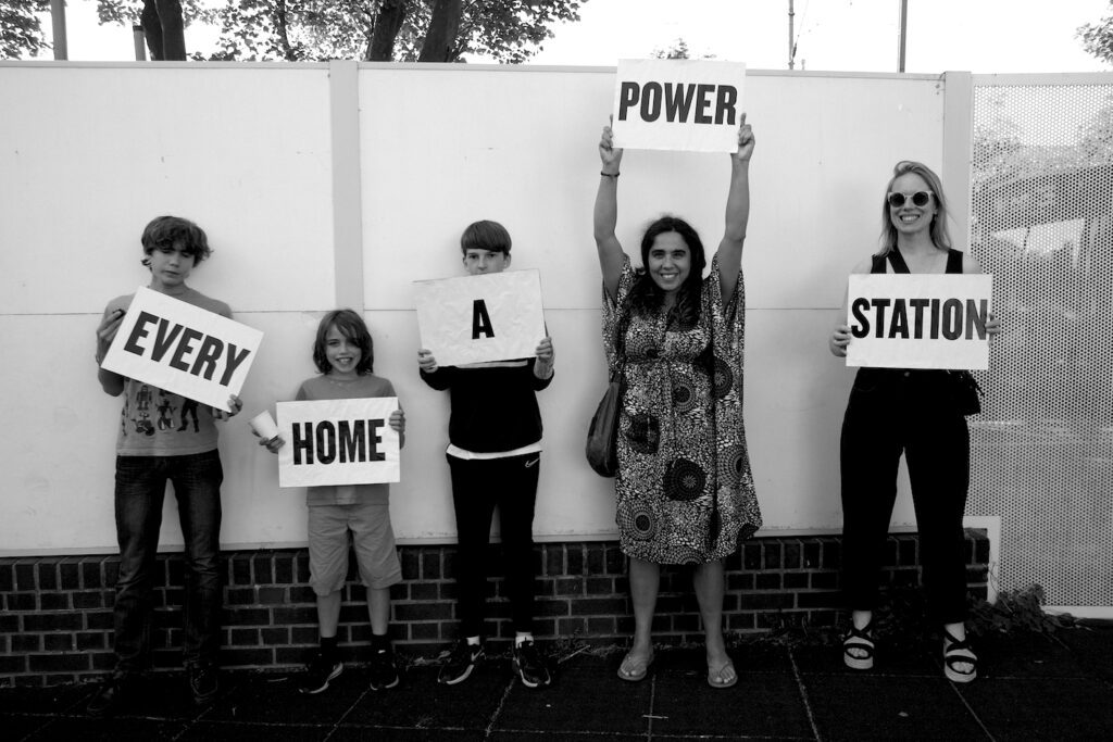 Children hold signs which read 'Every Home a Power Station'