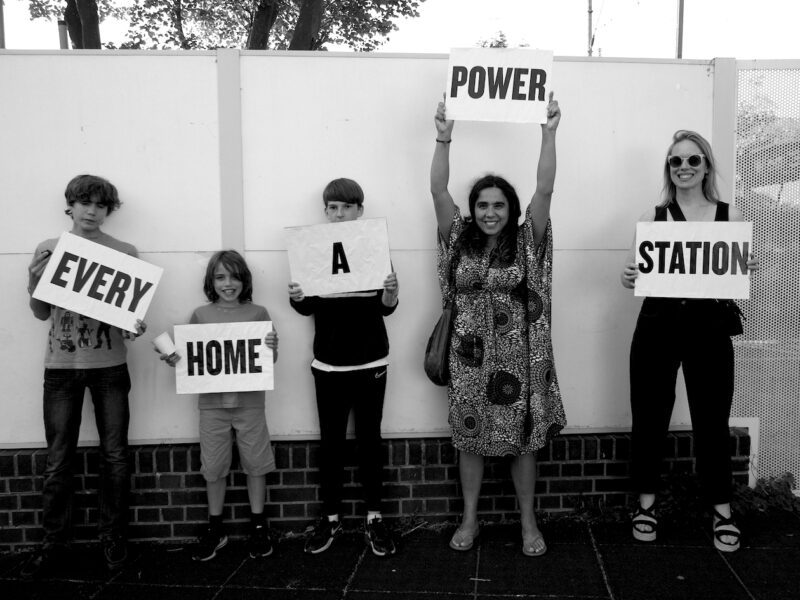 Children hold signs which read 'Every Home a Power Station'