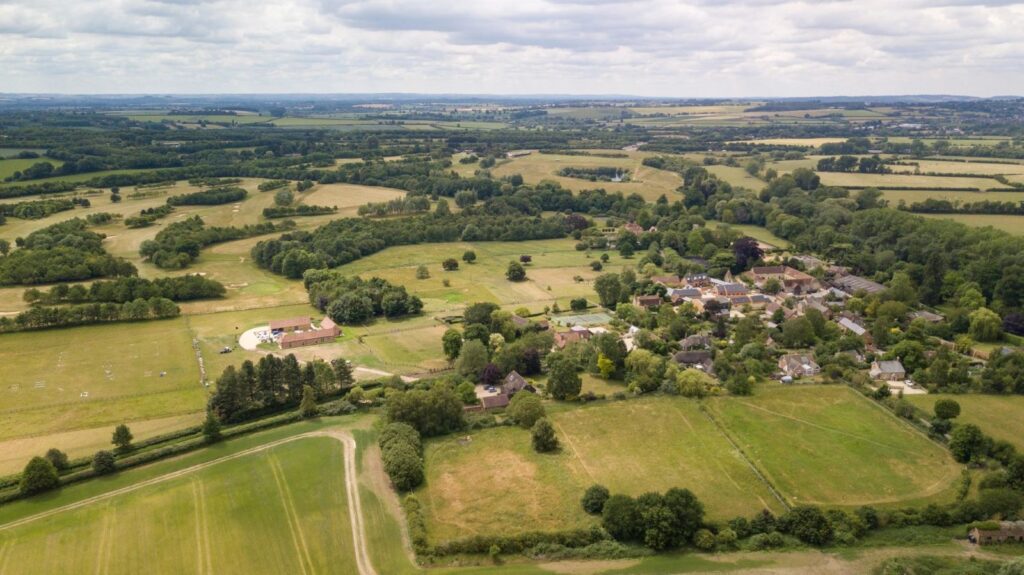 An aerial view of open countryside with Waterstock Village to the right and including part of the unintrusive golf course to the left.