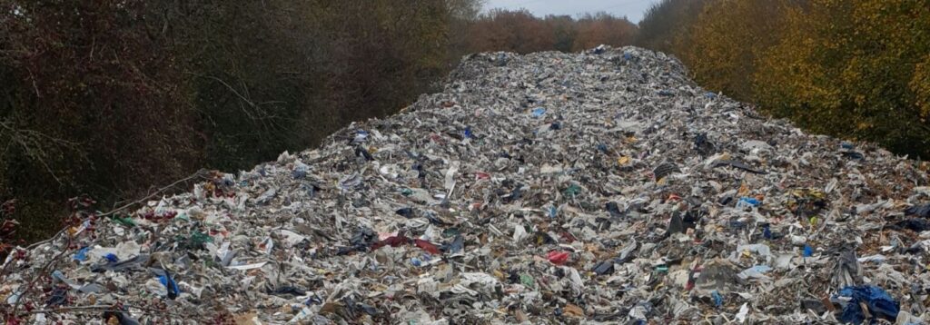 A pile of waste reaching into the disctance between hedgerows