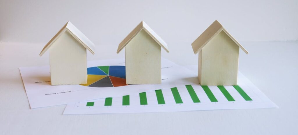 three small model houses sit on top of various graphs