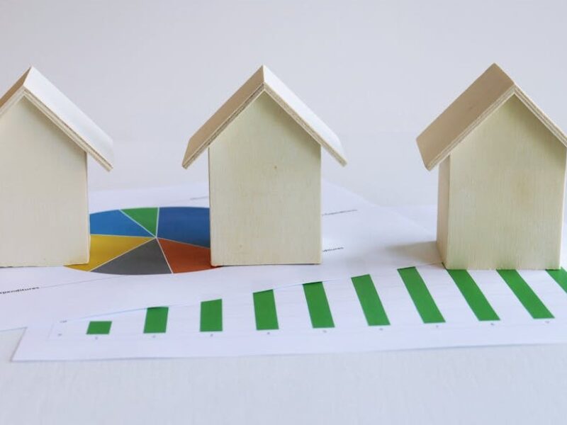 three small model houses sit on top of various graphs