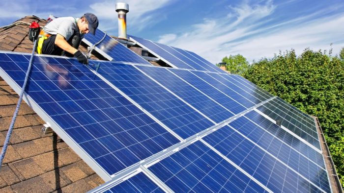 A man installing solar panels on a roof