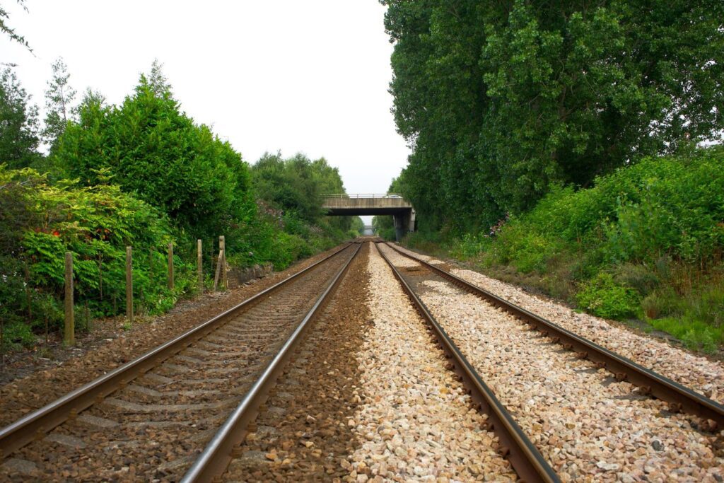 train tracks run into the distance with greenery on either side