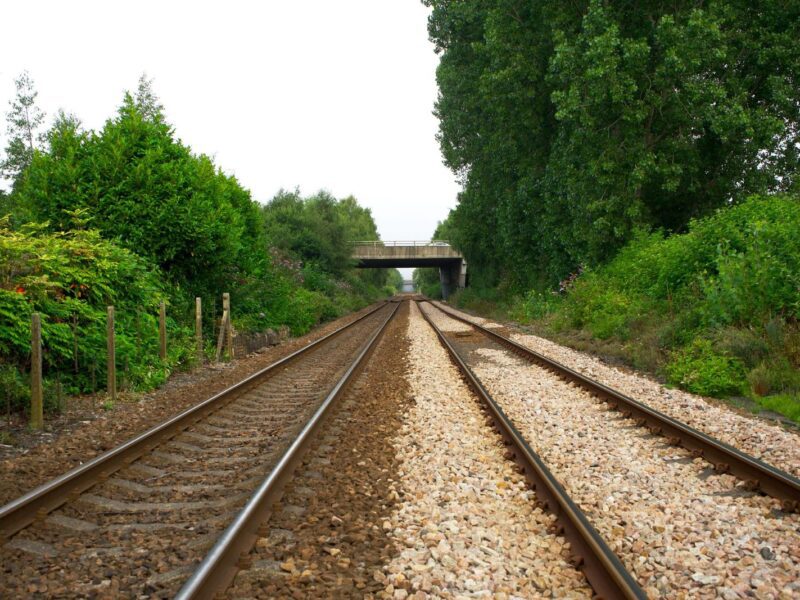 train tracks run into the distance with greenery on either side