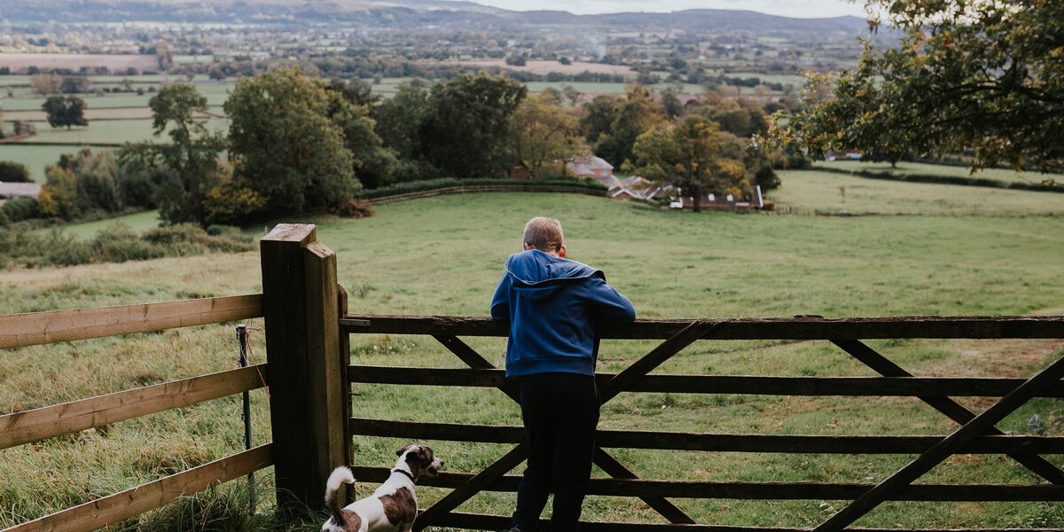 child and dog leaning on farm gate