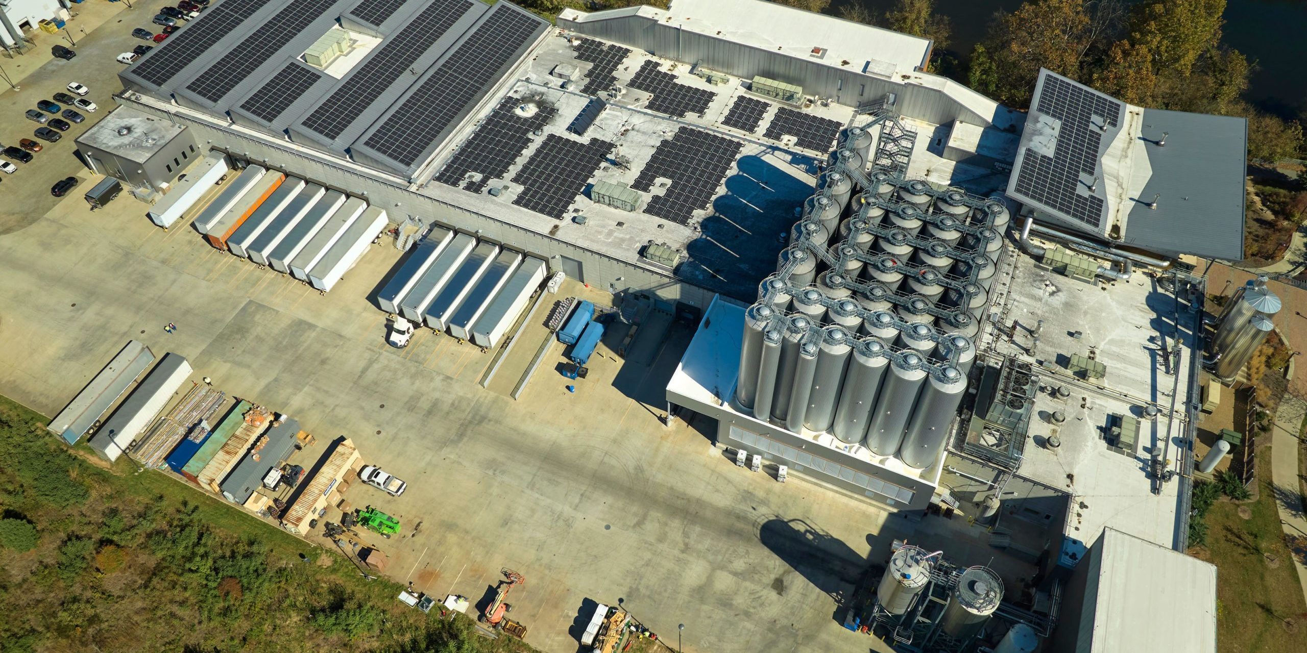 Aerial view of solar power plant with blue photovoltaic panels mounted on industrial building roof for producing green ecological electricity