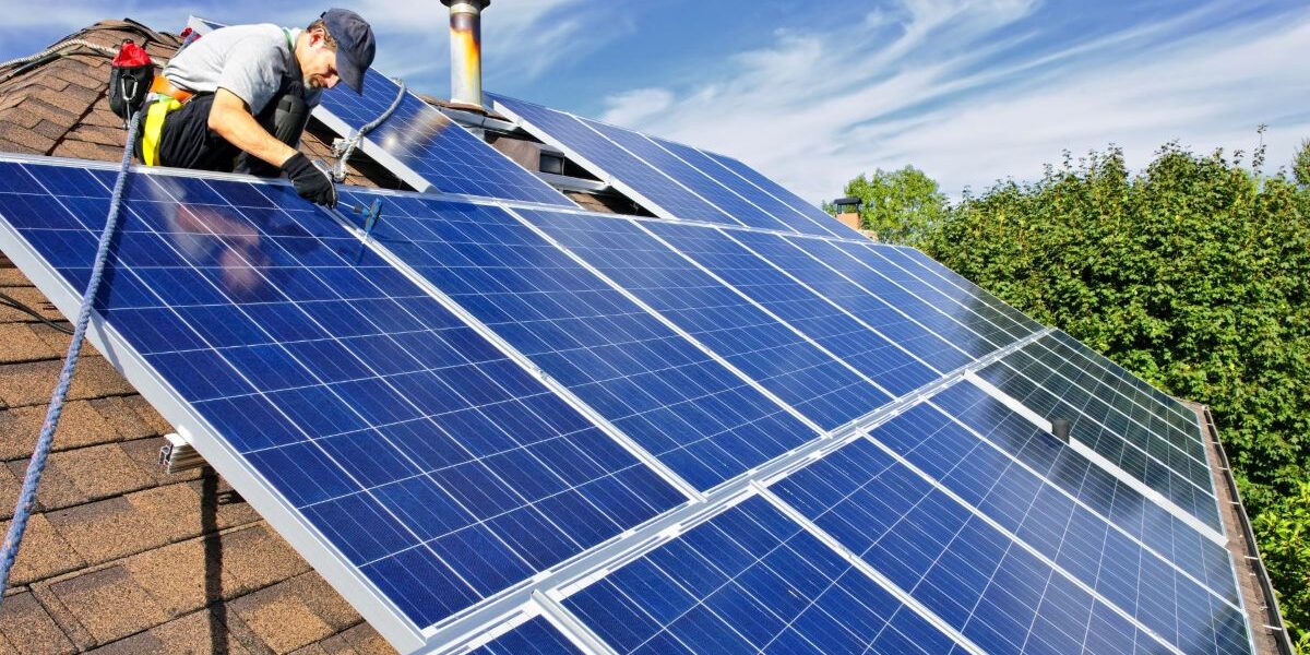 A man installing solar panels on a roof