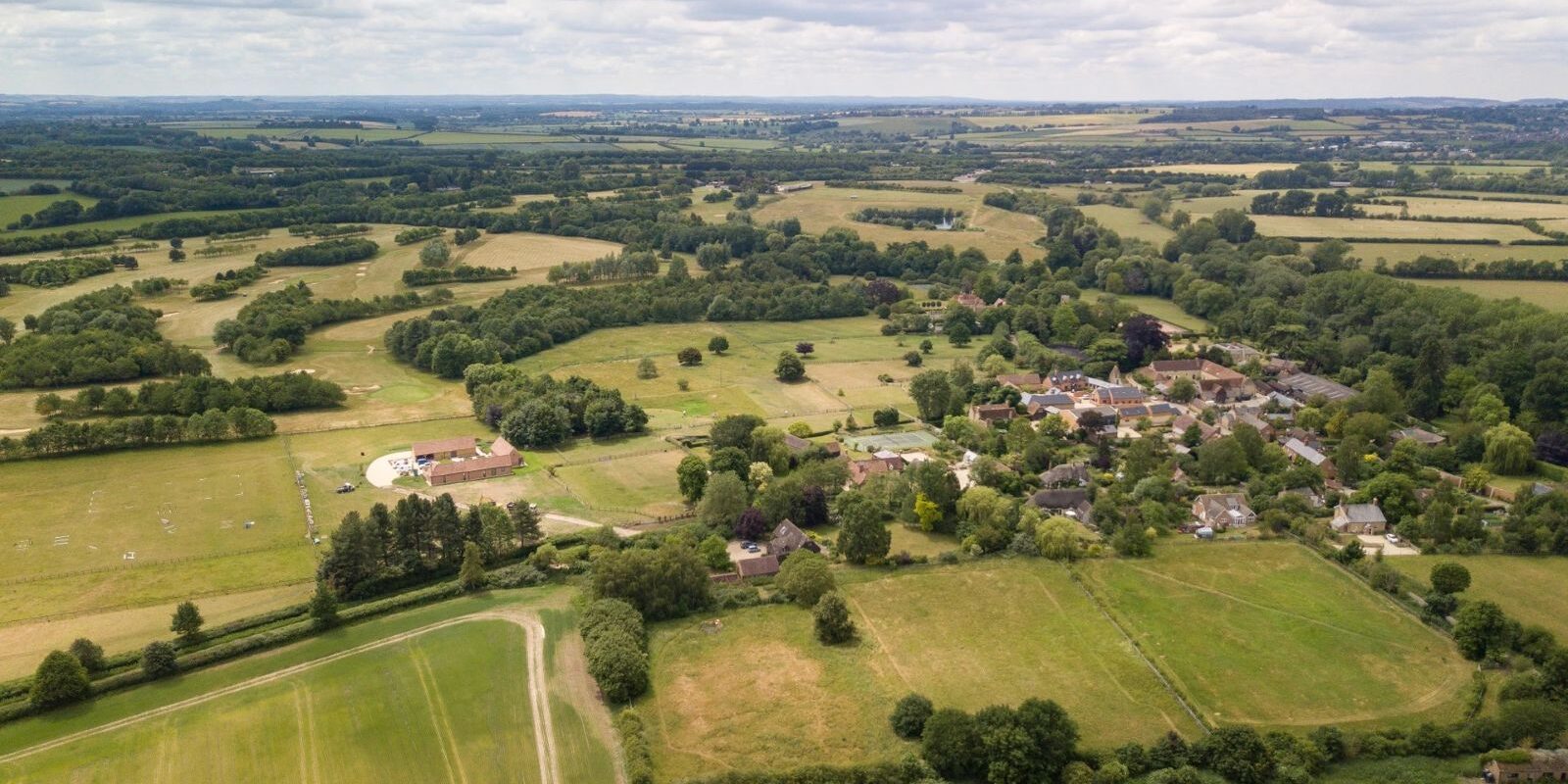 An aerial view of open countryside with Waterstock Village to the right and including part of the unintrusive golf course to the left.