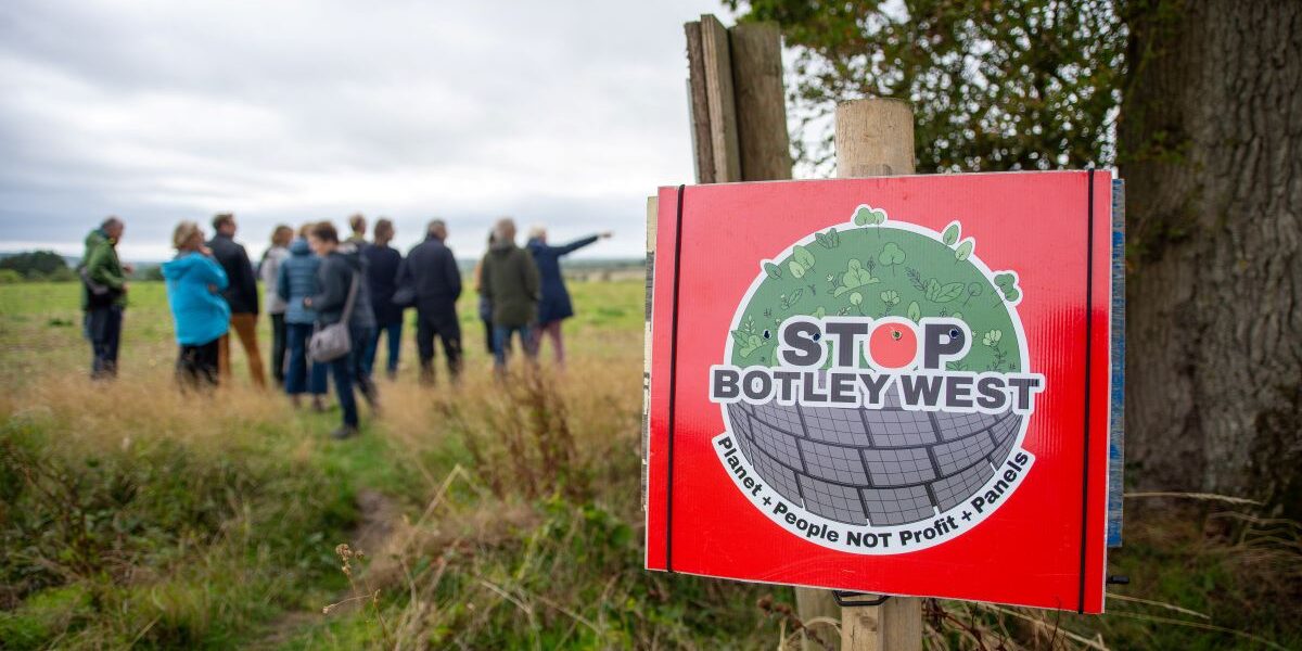 A 'Stop Botley West' placard with a group of people in the background