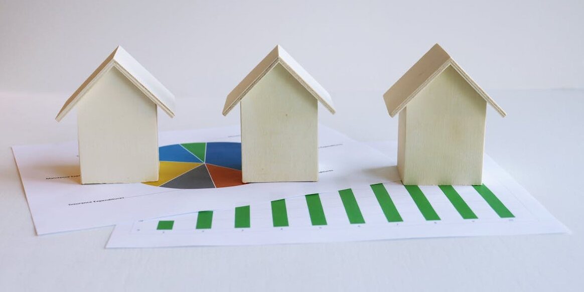 three small model houses sit on top of various graphs